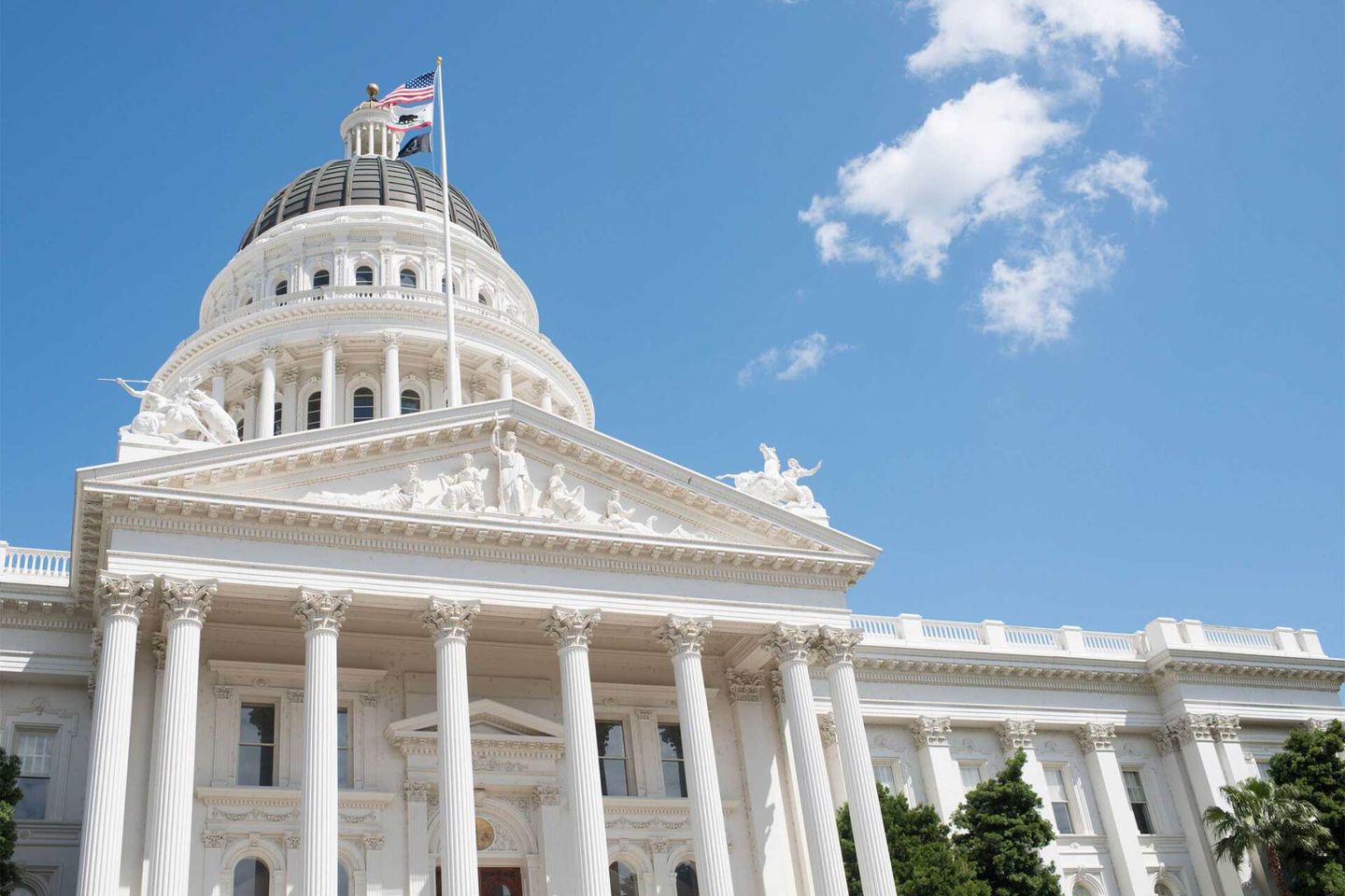 The California State Capitol in Sacramento beneath a clear blue sky.